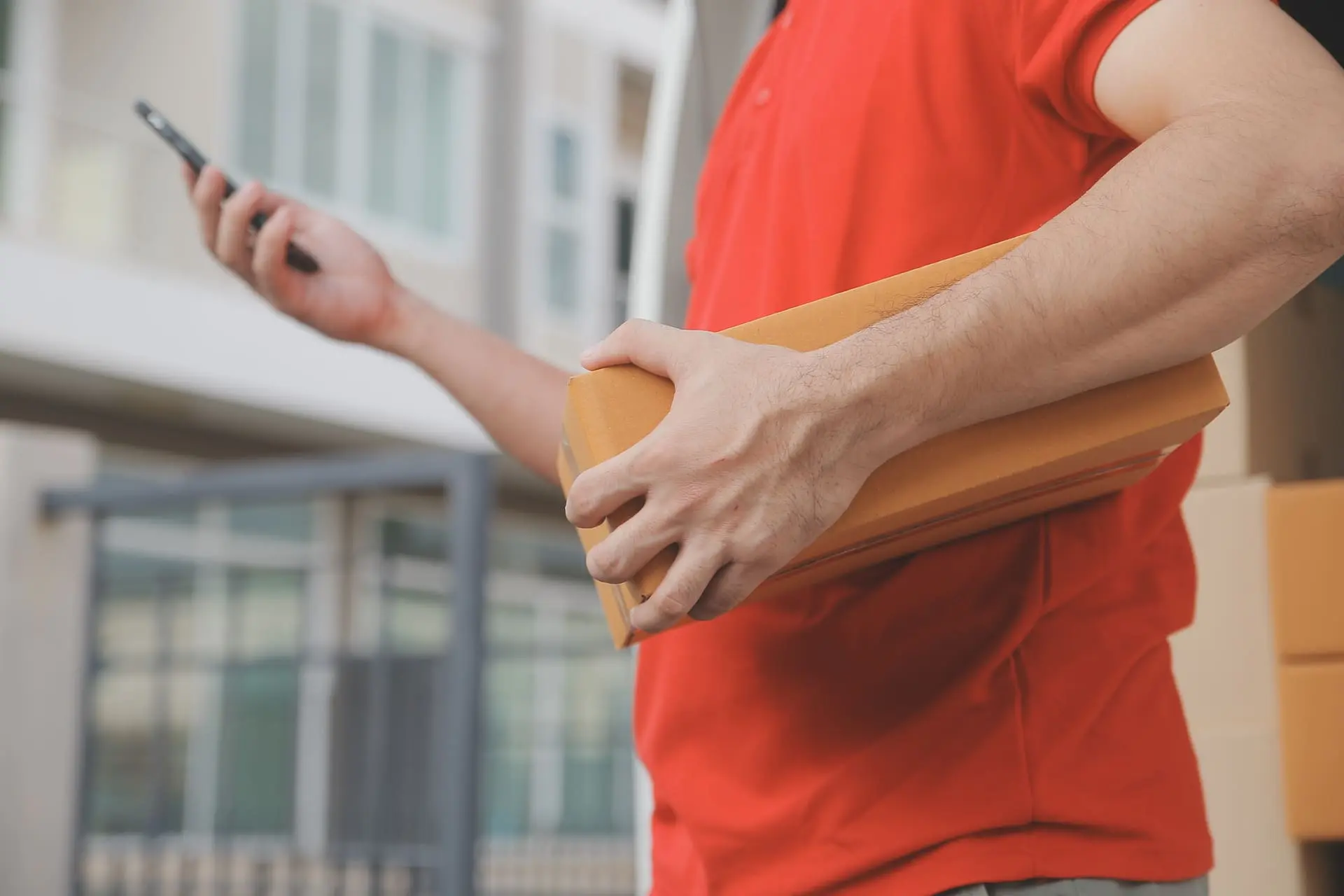Un livreur tient un coli et un téléphone dans ses mains