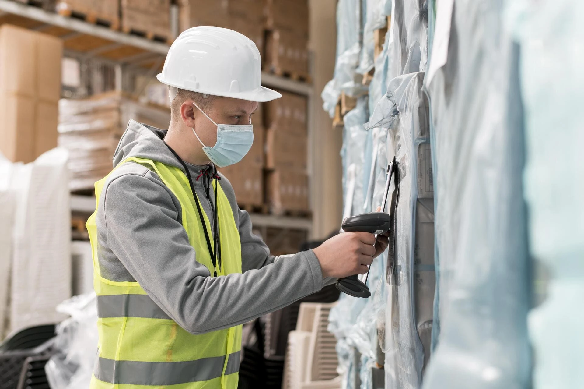 Travailleur dans un entrepôt avec un masque chirurgical effectuant des vérifications sur des marchandises