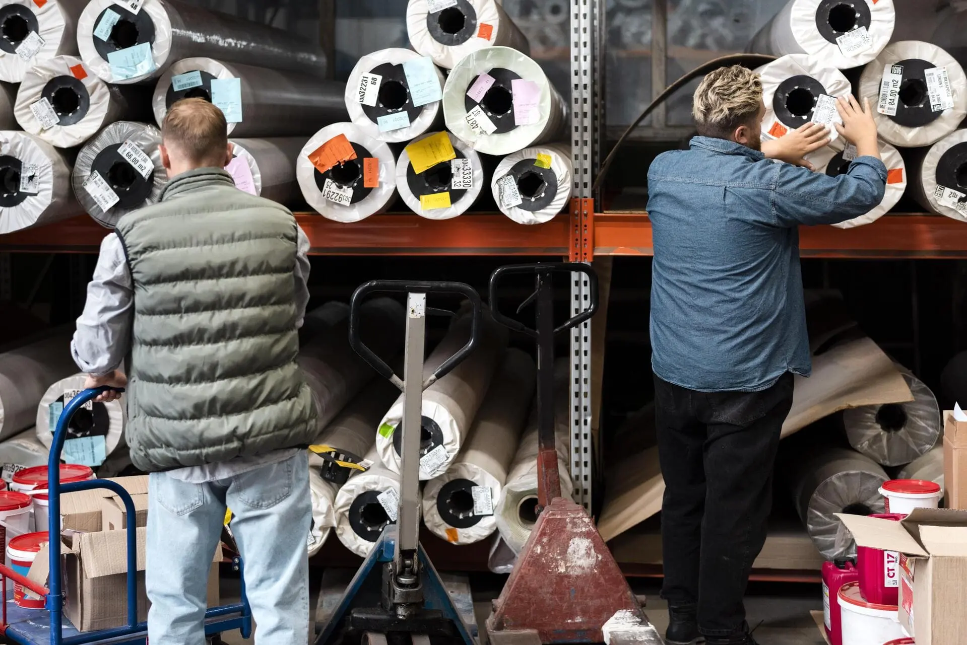 Deux hommes en train de ranger des rouleaux de textile