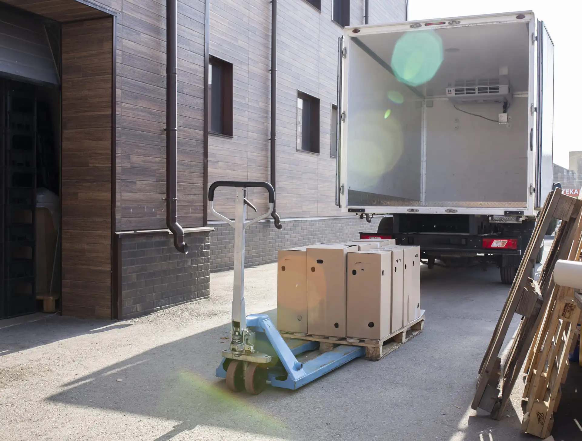 Transpalette avec des cartons dessus, devant un camion de dos